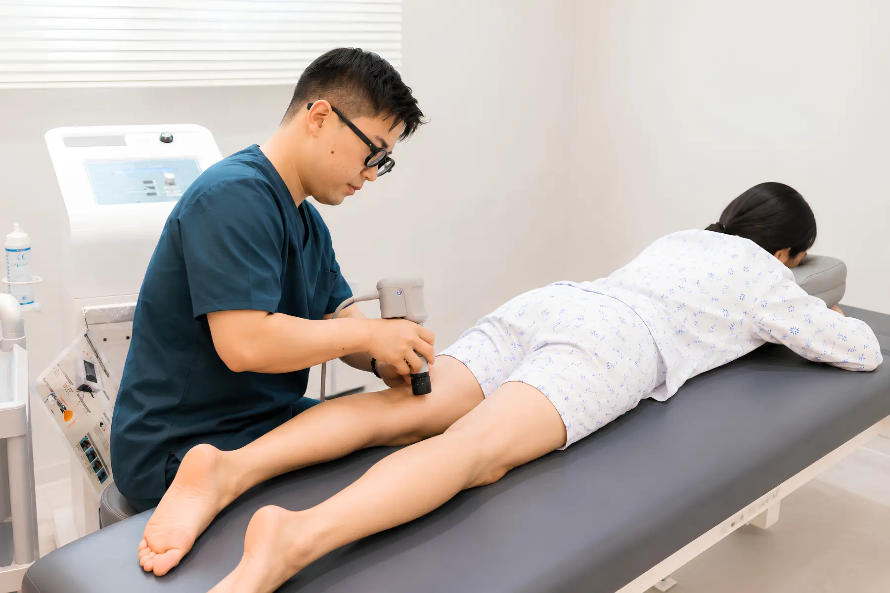 의료진이 체외충격파 장비로 환자 다리 통증 부위를 치료하는 모습