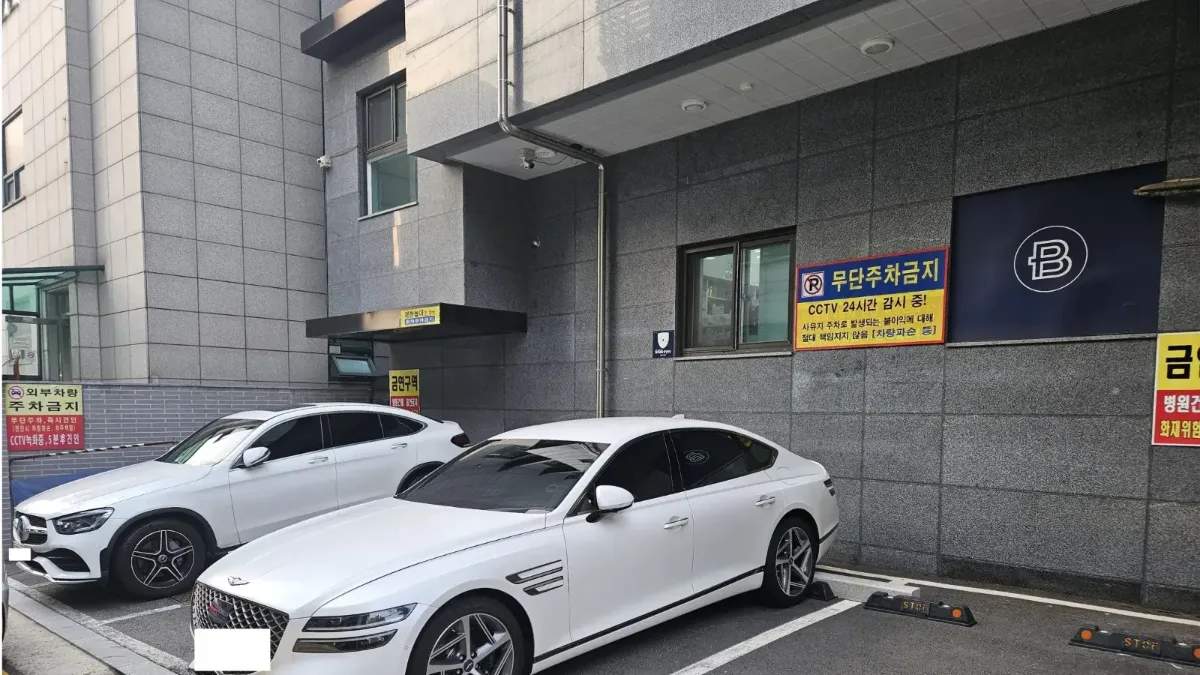 건물 뒤편 지상 주차장과 주차된 차량들